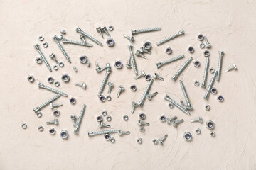 Different screws and chrome nuts on white grunge background