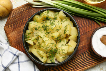 Bowl of tasty potato salad with green onion and salt, closeup