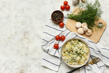 Bowl of tasty potato salad with ingredients and fork on light grunge background