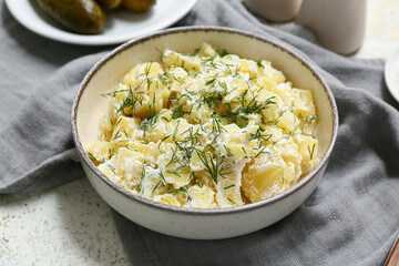 Bowl of tasty potato salad with dill and sour cream on light background