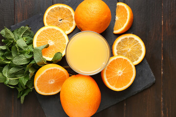 Glass of tasty juice with oranges and mint leaves on wooden background