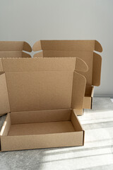 Three kraft cardboard boxes with open lids on a concrete table