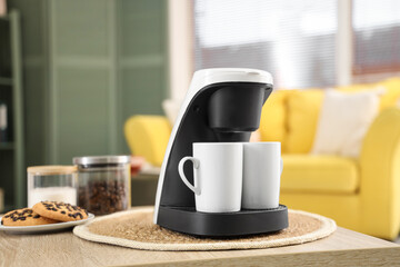 Coffee machine with cups on table in room, closeup