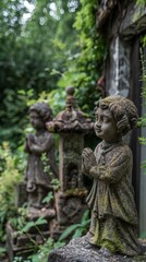 Obraz premium A pair of weathered garden statues depicting child figures, partially obscured by vibrant green foliage. The first statue, in the foreground, features a child with curly hair, hands clasped in a praye
