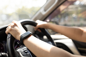 Woman driving a car with sunlight streaming through window, directly illuminating arms and...