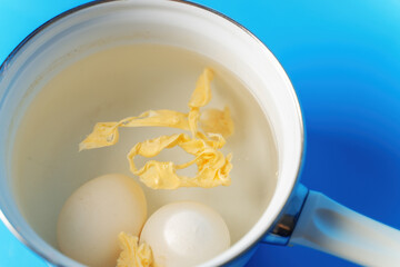 pot of boiled eggs showcases the fragility of life; one egg has cracked, spilling its vibrant yolk into the surrounding water, symbolizing imperfection and transformation