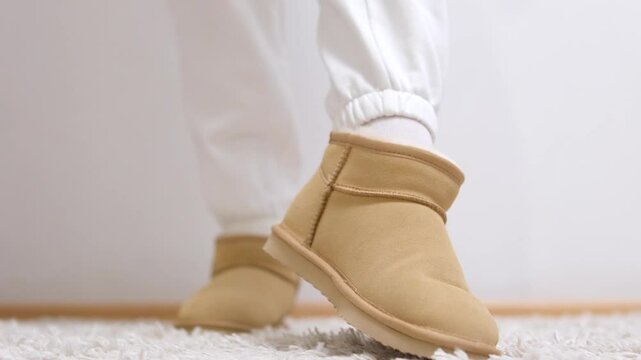 beige ugg boots Girl Waking Up Legs Feet In Bedroom. Comfort Cozy Morning. Awake Bedtime Early Morning. Female Slippers On Rug Near Sofa. Woman Legs Soft Plush Warm Slippers