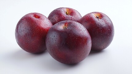Four plump, juicy plums with glistening skins sit closely together against a clean white backdrop, highlighting their rich purple hue and inviting texture, ideal for culinary inspiration