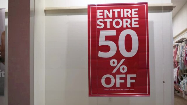 bold red sale poster displayed in retail store window announcing 50 percent off entire store Eye-catching signage promotes major discount event Red sale poster advertising 50 percennt off entire store