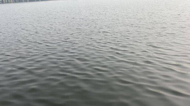 Continuous ripples and waves dance across the surface of the Narmada River, reflecting the sunlight in shimmering patterns