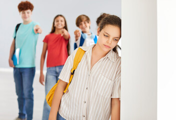 Outcast sad preteen girl suffering from bullying, feeling lonely and excluded, standing alone with...