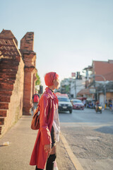 Fototapeta premium Gen z girl leather fashion with punk Asian woman tourist of local city Southeast Asia travel trendy pink hairstyle young female punk traveler walking around in town