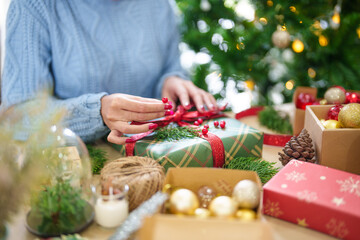 Woman in knitted sweater wrapping christmas presents with eco paper girl packing christmas gifts Xmas holiday concept