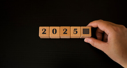 Woman holding wooden blocks with calendar icon and text "2025" placed on table. Goals, plans, intentions, strategies, plans, start, budget, mission, action, inspiration and new year concept.