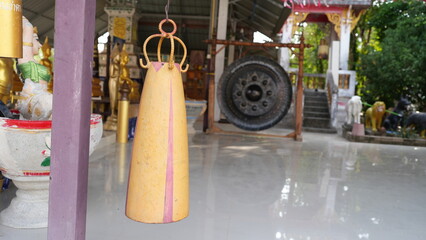 Yellow Temple Bell Hanging with Background of Religious Artifacts