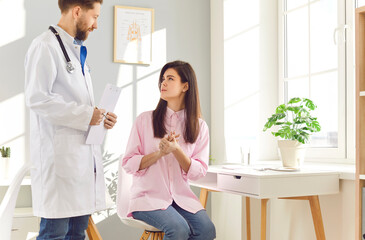 Doctor or nurse is talking to a female patient during a medical consultation in a hospital office....