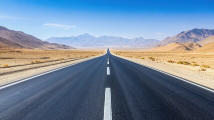 Naklejka premium A vast, open road stretches through a parched desert landscape, framed by distant mountains under a clear blue sky.