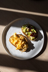Breakfast plate of bread with scrambled eggs and avocado.