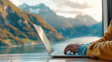 A serene workspace by a lake, with a person typing on a laptop, surrounded by majestic mountains and nature.