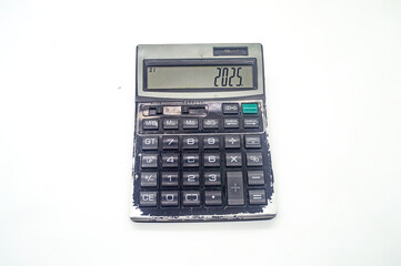 An old, worn out calculator displaying the number 2025 on its screen. The calculator has visible...