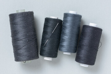 Black grey gray thread spools with needle background with copy space for text close-up flat lay top...