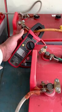 electrician working on a power station, Checking current in power line by using clampmeter.