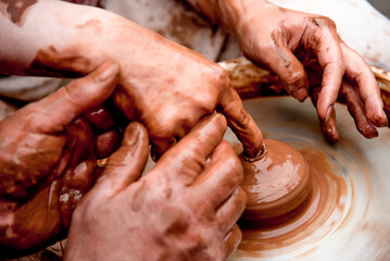 Potter sculpts mug from clay, close up dirty hands create vase on ceramist wheel