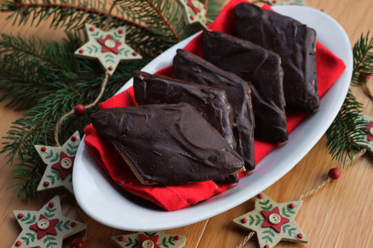Italian traditional festive cookies called Mostaccioli or Mustaccioli on a plate on red tablecloth on wooden table. Christmas cookies made mith Pisto, a mix of various spices