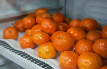 Tangerines or Mandarin oranges displayed in a refrigerator are suitable for use in poster designs, or as illustrations for articles about fruits.