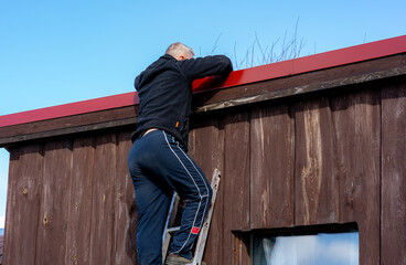 A man climbs the stairs on the roof of a small country house