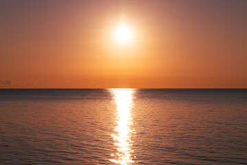 A breathtaking view of the sun setting over the horizon, casting a golden glow on the calm ocean waters. 