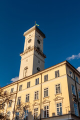 A tall white building with a clock tower and a green flag on top