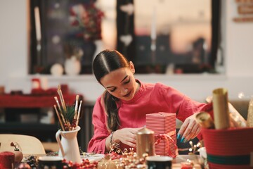 Surrounded by twinkling lights and colorful decorations, a woman happily wraps gifts at a table overflowing with festive supplies. Her creativity shines in this cheerful holiday activity