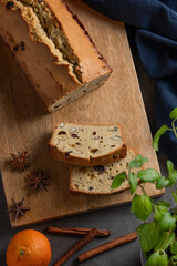 Spicy pie with fruits, nuts and spices on a wooden board, on a dark background