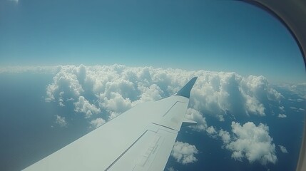 Looking out from inside the airplane, seeing the wing against fluffy white clouds contrasting with the bright blue horizon, capturing the joy of air travel