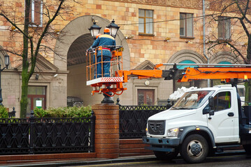 Aerial platform truck with electricians in lift bucket replacing led light bulbs during street lamp...