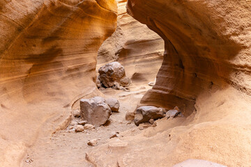 A cave with a small opening and rocks in the background