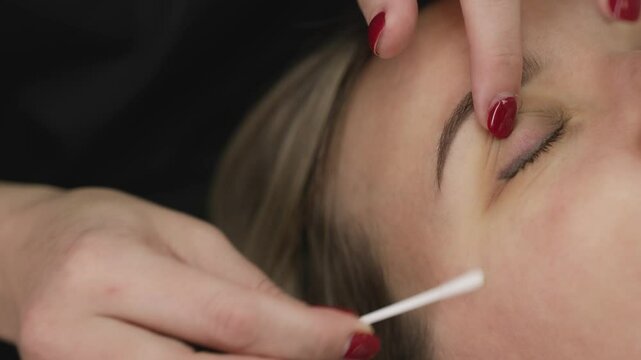 Preparing eyes for eyelash extensions, beauty salon. A woman is preparing for the eyelash extension procedure.