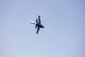 Turning Power. F-16 fighter jet executes a tight turn with its afterburner ablaze during a dazzling...