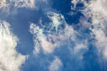 Obraz premium Ethereal Clouds with Rainbow Hues. A mesmerizing view of wispy clouds against a deep blue sky, adorned with subtle rainbow colors formed by sunlight diffraction.