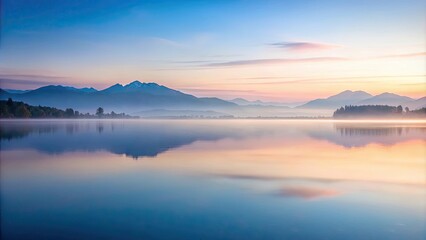 Obraz premium Serene sunrise over tranquil lake with misty mountains reflecting in calm water
