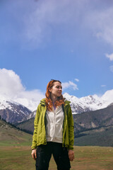 Naklejka premium A young girl in bright clothes smiles against the background of snowy peaks in a mountain valley