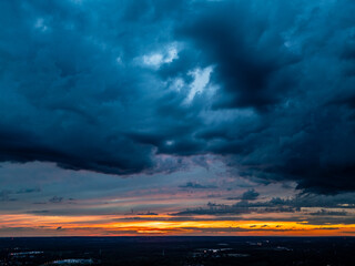 Stormy Sunset Drama. Intense dark clouds dominate the sky while a vibrant orange and yellow sunset...