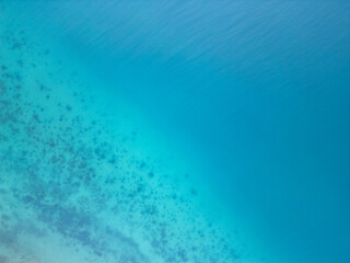 Gradient of Turquoise Waters.  A stunning aerial shot capturing the seamless gradient of turquoise to deep blue, highlighting coral reefs and crystal-clear waters near the shoreline.