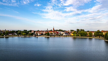 Charming View of Lake Raduń in Wałcz, Poland. A picturesque view of Lake Raduń with colorful houses, lush greenery, and serene waters, reflecting the peaceful town