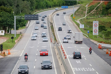 Transito de veiculos intenso na rodovia dos tamoios litoral norte da praia com fundo de natureza e represas.