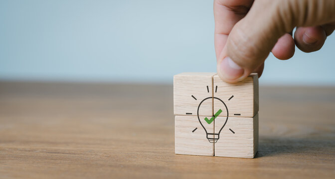 A fix. Icons of wooden cubes with lightbulb on hand are placed on grey backdrop with copy space. Business analysis, recommendations for business strategies. Concept of consultation, suggestion.