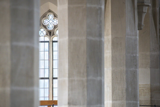 Gotisches Kirchenfenster mit Rosette, Ma&szlig;werk und  Bleiverglasung hinter unscharfen achteckigen Steins&auml;ulen in der Stiftskirche in Dettingen an der Erms