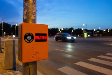 Pedestrian zebra crossing with text telling people to wait and press button in German