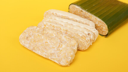Raw Tempeh or Tempe isolated on yellow. Tempe Made From Fermented Soybeans. 
